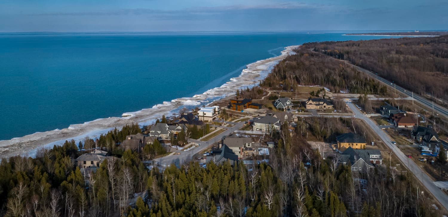 Winter shoreline with ice along the beach and homes above the bluff