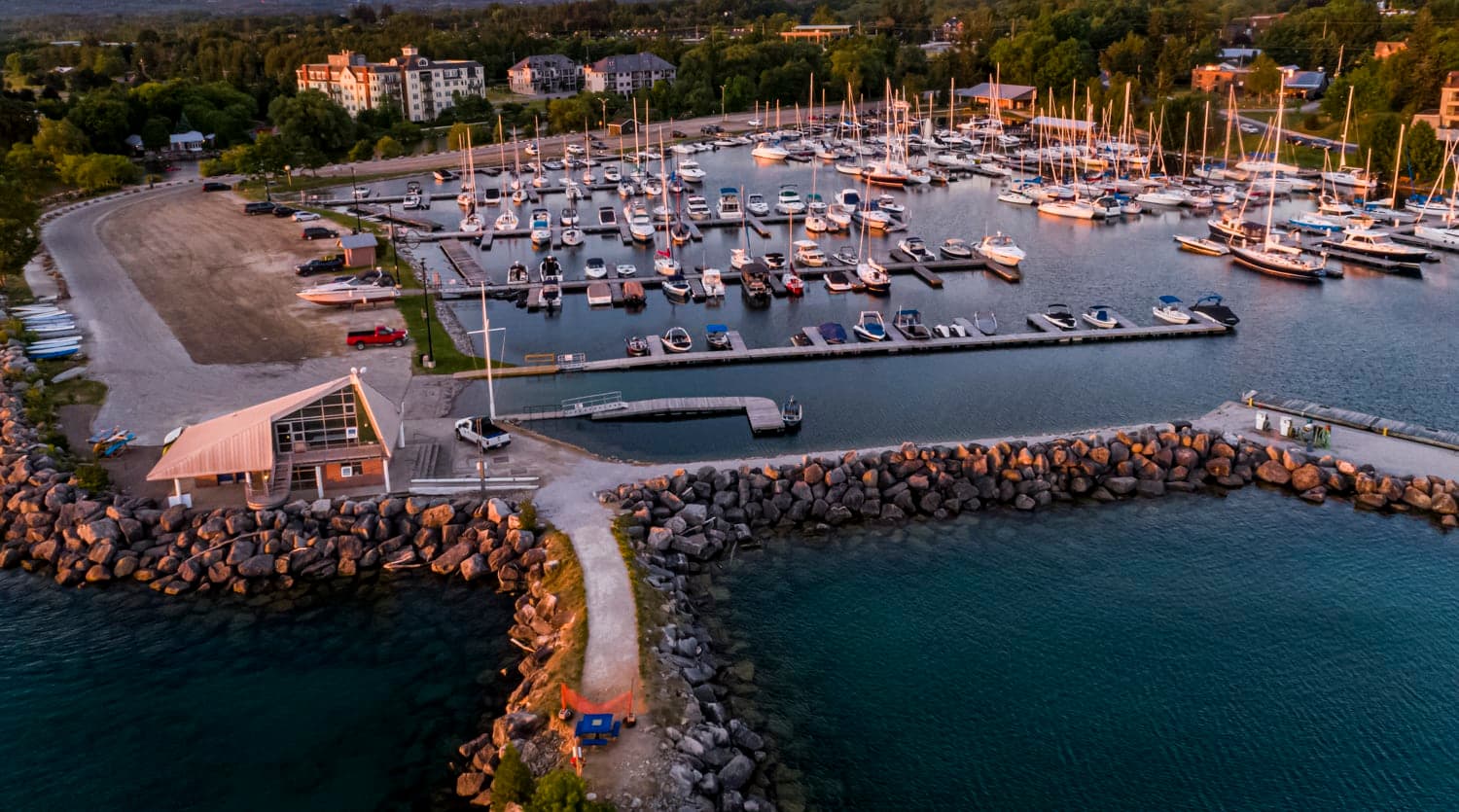 Marina full of docked sailboats along a stone breakwater