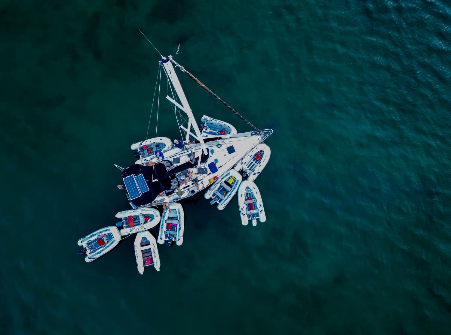 Sailing catamaran with crew and tender dinghies on open water