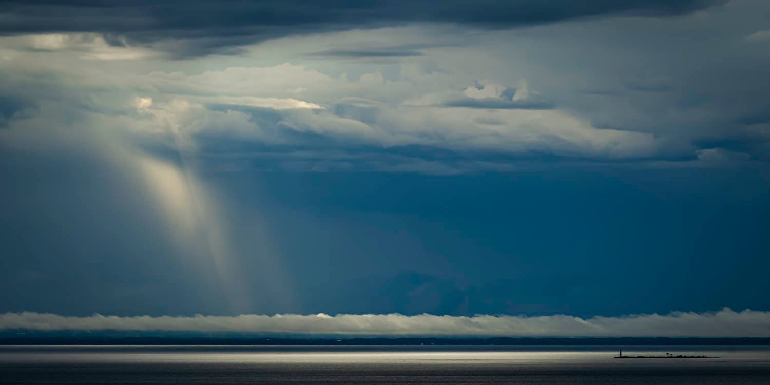 Sunbeams breaking through storm clouds over open water