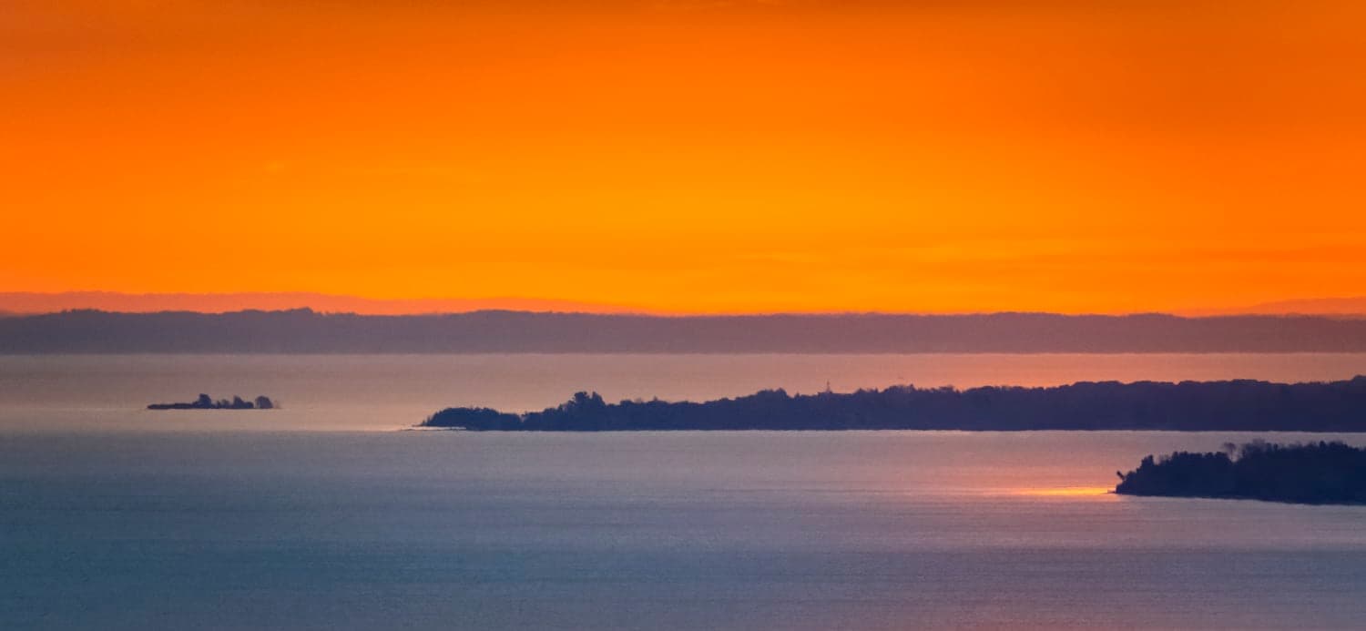 Orange sunrise over island silhouettes on the bay