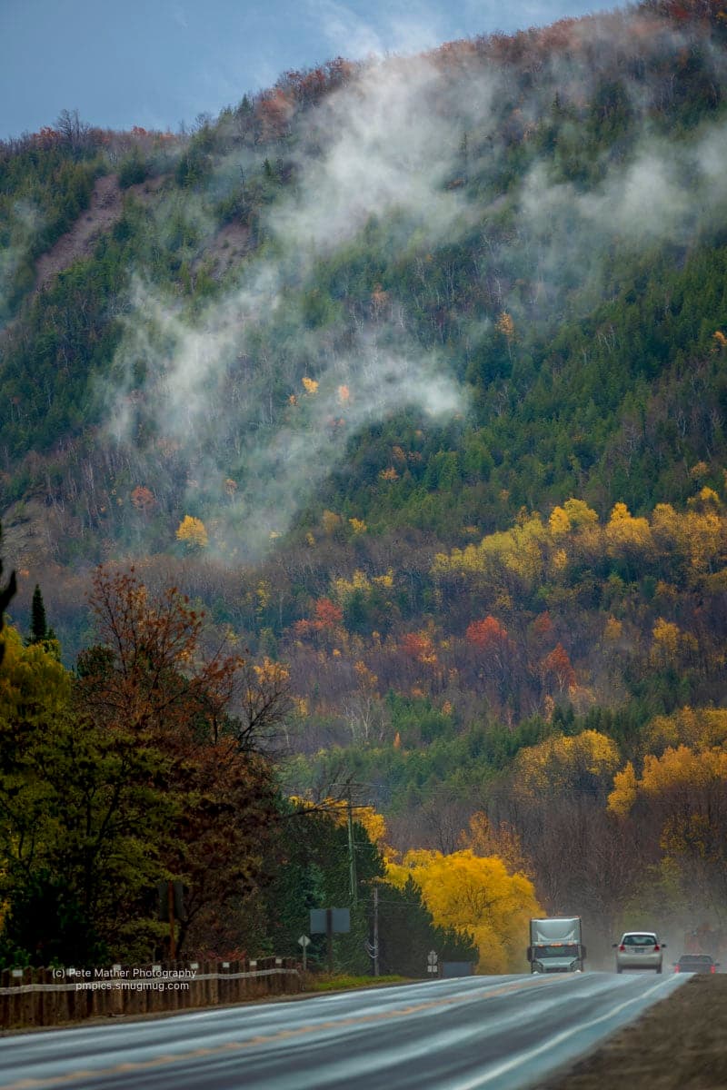 Mist rising off an autumn hillside above the highway