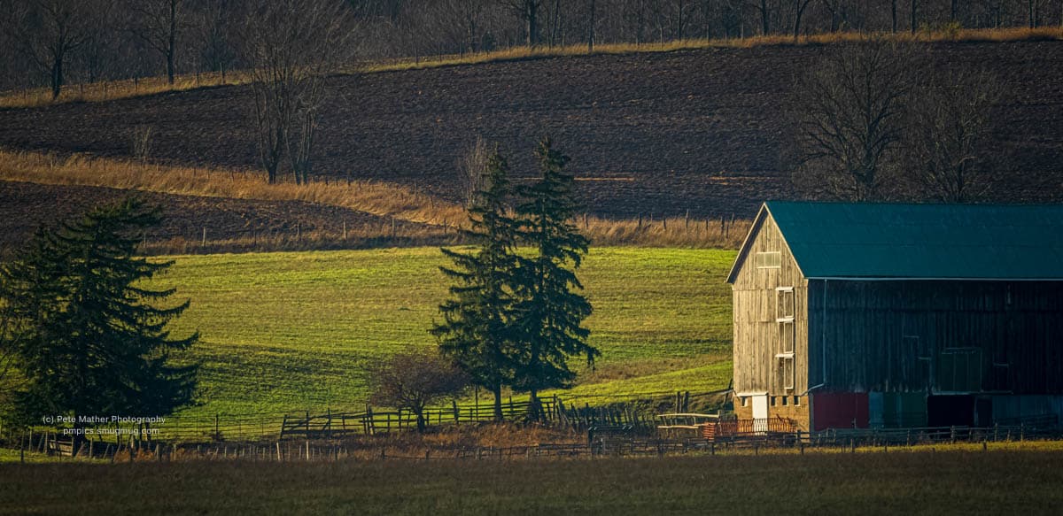 Weathered barn above green pasture and layered fields