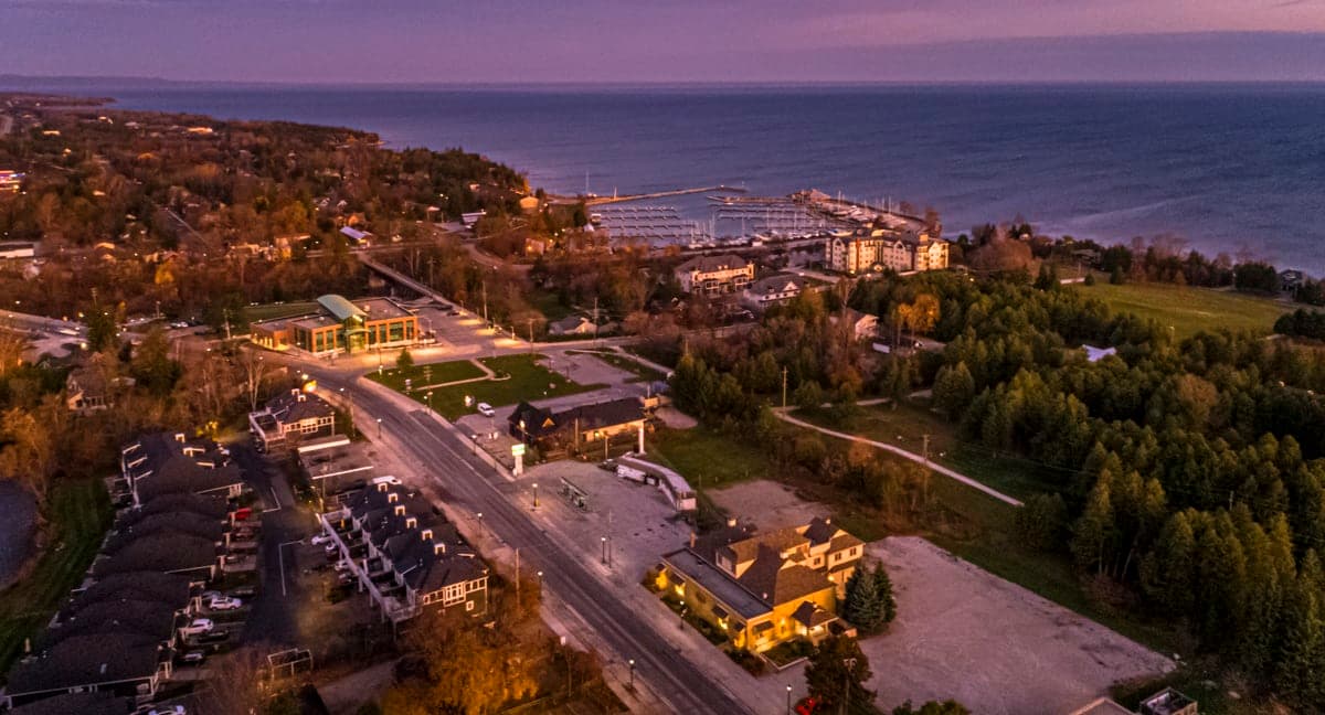 Harbourfront town lit up at dusk, marina and shoreline beyond