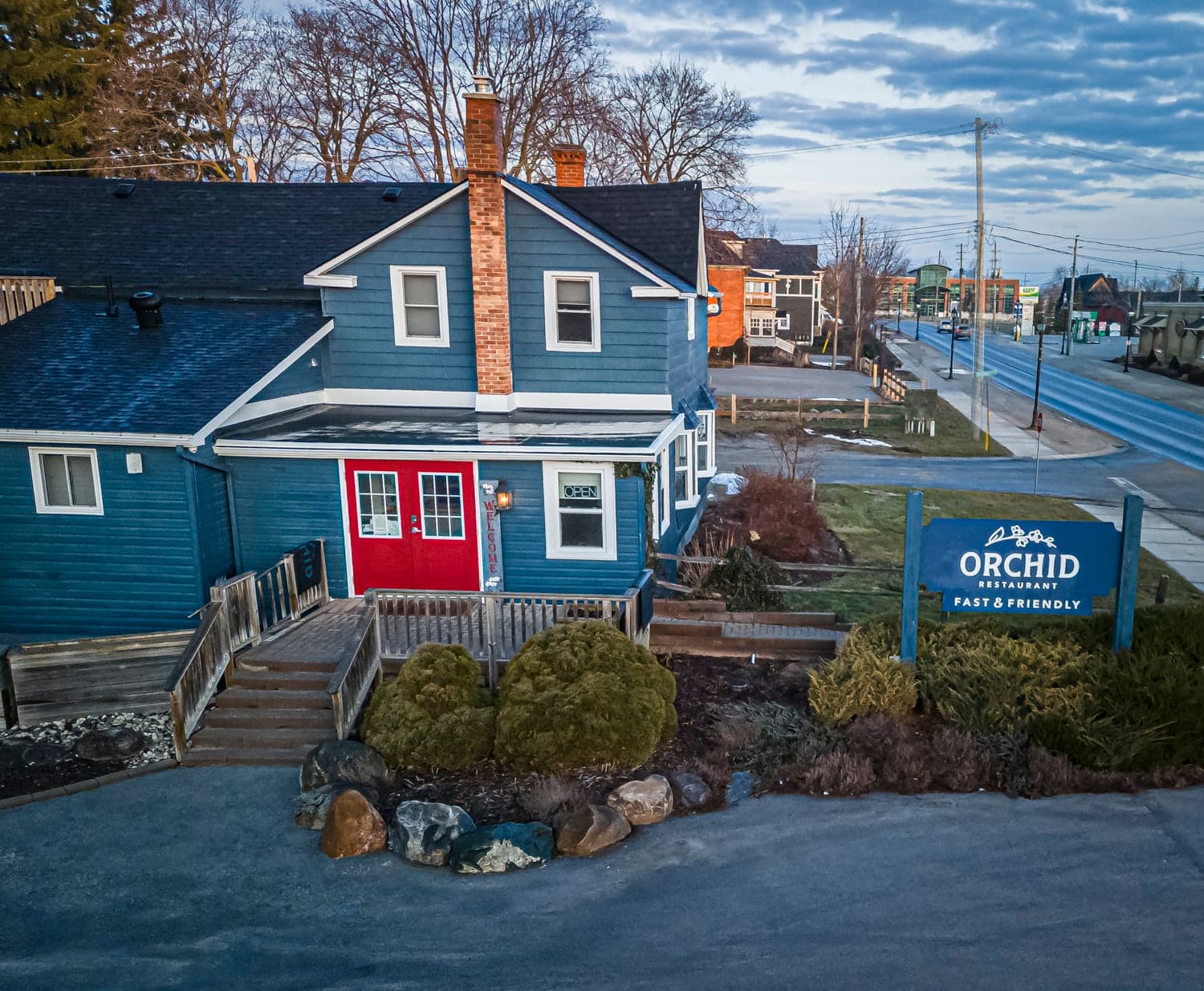 Restaurant storefront with a welcoming red door at dusk