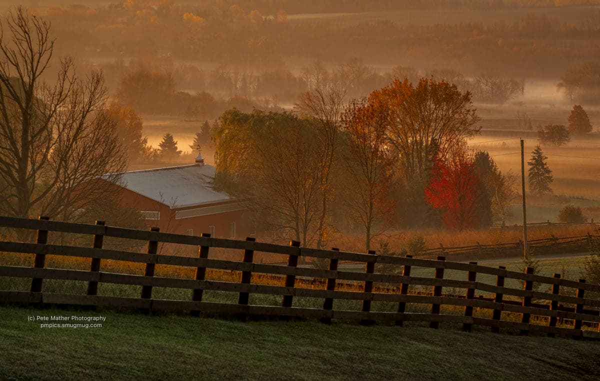 Fog settled over a valley farm at sunrise